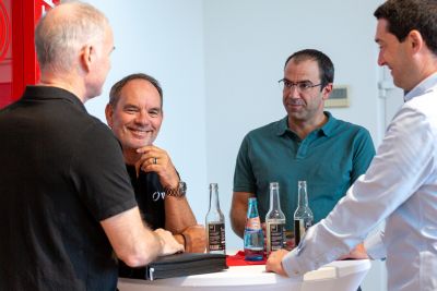 Four people in technical discussion at a standing table in front of the IDT exhibition stand