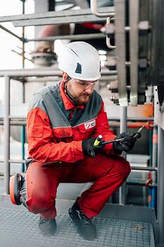 Flange fitter crouching while assessing a flanged connection