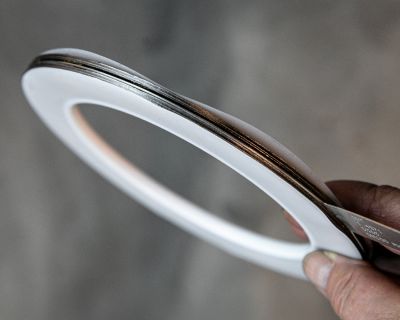 Hand holding a ring-shaped PTFE flat gasket with metallic core layer