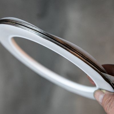 Hand holding a ring-shaped PTFE flat gasket with metallic core layer